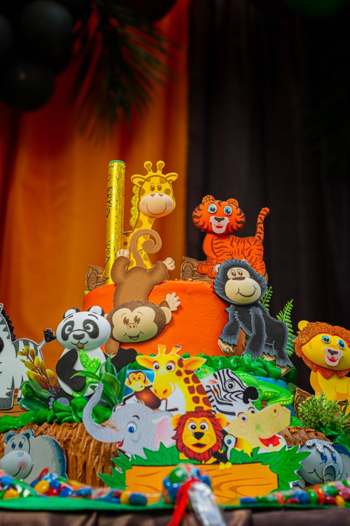 Colorful jungle-themed cake with animal decorations for a child's birthday party.