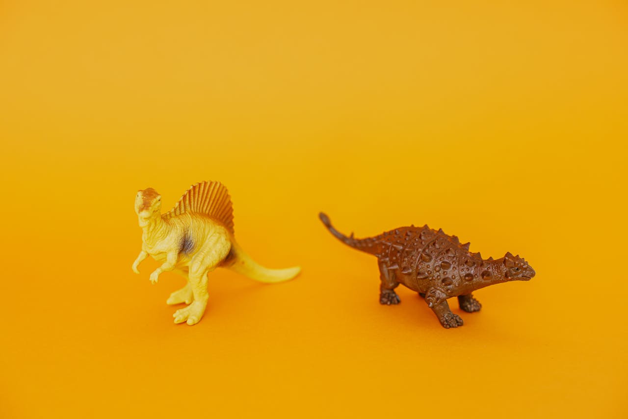 Plastic dinosaur toys displayed against a bright yellow background.